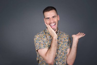 Pozitif memnun adam der ki: Vay be, ne kadar heyecan verici, şaşırtıcı bir ifade, bir şey ifade ediyor. Neşeli genç adam bir şeyler gösteriyor. Bir eli kafasında, diğer eliyle işaret ediyor..