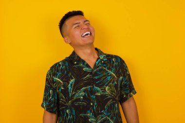 Neşeli İspanyol adam eğleniyor ve güzel şakalara gülüyor ya da gri duvara yaslanmış günlük kıyafetler giyiyor. Mutlu adam içeride poz verir..