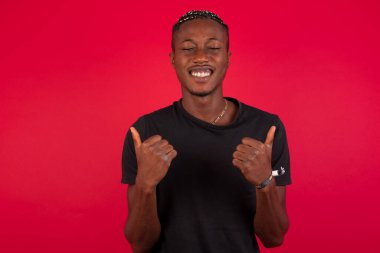 Arka planda izole edilmiş, olumlu içerik ve mutluluk duyguları gösteren genç, iyimser Afrikalı Amerikalı adama yakın çekim. Ortak alan, kalite ve tavsiye ile tatmin kavramı.