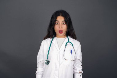 Şaşkın bakışlarla kameraya bakan, şaşırmış ve şaşırmış genç doktor kadın Omg ya da Wow diye bağırıyor.