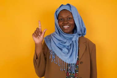 Hoş görünümlü Afro-Amerikan Müslüman kadının yakın portresi zekice bir ifadeye sahiptir, bir parmağını kaldırır, önemli bir şeyi söylemeyi unutmaması gerektiğini hatırlar. Kapalı