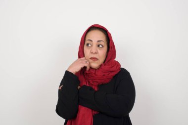 Düşünceli Müslüman kadının portresi elini çenesinin altında tutuyor, bir şey hatırlamaya çalışıyor ya da ilgiyle bir şey dinliyor, gündelik kıyafetlerle. Stüdyoda poz veren başörtüsü takan orta yaşlı bir Arap kadın.