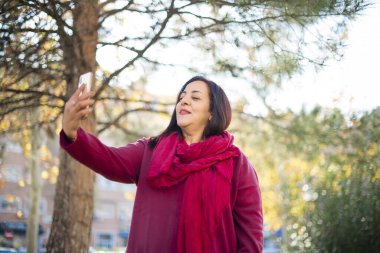 Güzel orta yaşlı Arap kadın parkta selfie çekiyor.  