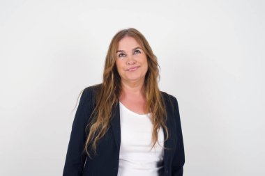 Kafası karışık, beyaz, orta yaşlı bir kadın yüzünü buruşturur, dudaklarını ısırır, kaşlarını kaldırır, yukarı bakar, sorunları olur, şık giyinir, gri arka planda soyutlanır, pişman olur..