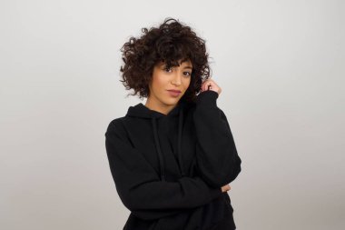 Neşeli, güzel bir genç bayanın, gri duvarın karşısında, yüzünün yanında durduğunu hayal et. İyi haberleri dinledikten sonra kameraya mutlu bir ifadeyle bakmak. Kendine güvenen kız..