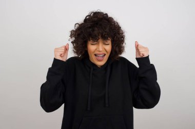 Kafkasyalı esmer kadın başarısını ve zaferini sevinçle kutluyor ve yumruklarını zevkle sıkıyor. Hedeflerine ve hedeflerine ulaşmaktan mutlu olan şanslı kadın. Olumlu duygular, duygular.