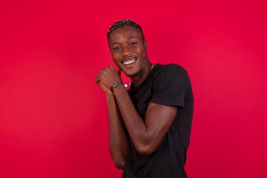 Hayalperest Afro-Amerikan bir adam, hoş bir ifadeyle, gözlerini kapatıyor, ellerini yüzüne çarpıyor, hoş bir şeyler düşünüyor, arka planda poz veriyor..