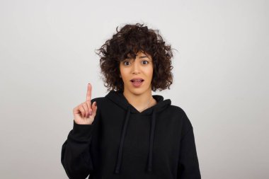 Hoş görünümlü kadın modelin yakın portresi zekice bir ifadeye sahiptir, bir parmağını kaldırır, önemli şeyleri söylemeyi unutmaması gerektiğini hatırlar. Kapalı