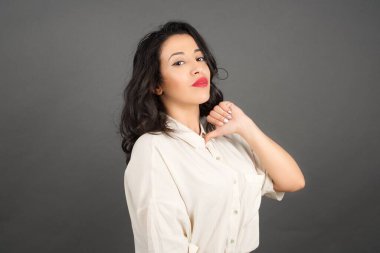 Kendini gösteren güzel esmer kadın. Gri arkaplanda duruyor. 
