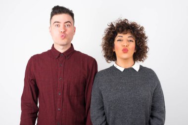 Çekici çift doğrudan kameraya bakar, memnuniyetini ifade eder, stüdyo arka planında izole olur. İnsanlar, vücut dili kavramı.