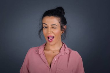 Sevimli genç esmer kadın mutlu bir ifadeyle gözlerini zevkle kırpıyor. Yüz ifadeleri ve insanların duygu konsepti.