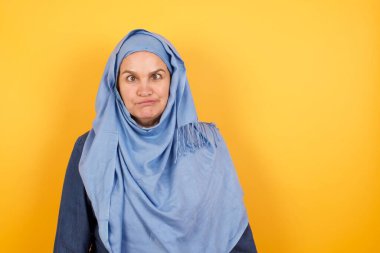 Komik orta yaşlı tesettürlü Müslüman kadın gözlerini kıstı, dudaklarını buruşturdu, bütün gün çalıştıktan sonra suratını buruşturdu, aptallaştırdı.. 