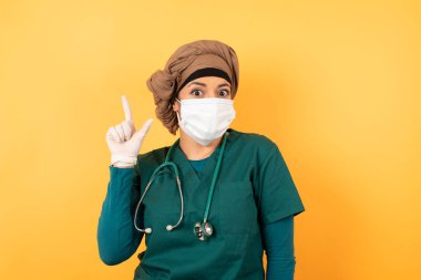 Yüzünde maske olan Arap kadın doktorunun yakın portresi zekice bir ifadeye sahiptir, bir parmağını kaldırır, önemli bir şeyi söylemeyi unutmaması gerektiğini hatırlar. Kapalı