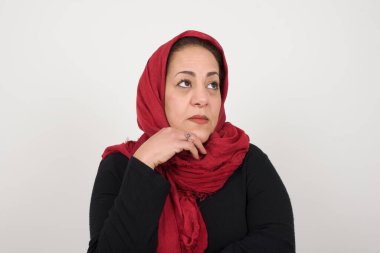 Yüz ifadeleri ve duygular. Düşünceli olgun müslüman kadın başının altında el ele tutuşuyor, şüpheli bakıyor. 