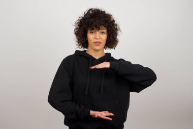 İzole edilmiş arka planda genç ve güzel bir kadın. Elleri büyük ve büyük bir işaret, ölçü sembolü gösteriyor. Kameraya bakıp gülümsüyor. Ölçüm konsepti.