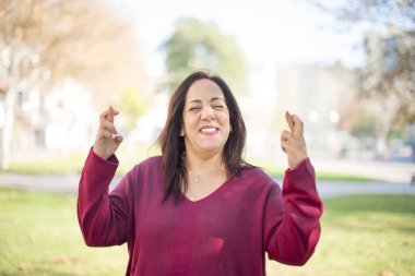 Parkta çapraz parmakları olan orta yaşlı güzel bir Arap kadın.  