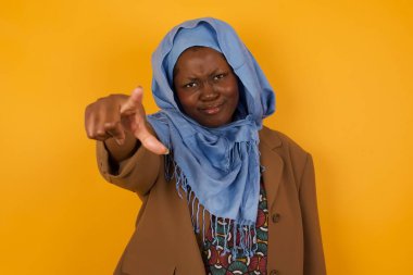 İçeriden çekilen, sıradan giyinmiş, neşeli, Afro-Amerikalı Müslüman kadın fotoğrafı size mutlulukla bakıyor, rekabeti seçiyor, olumlu bir ifadeye sahip. Güzel zeki öğrenci seçimini yapıyor.