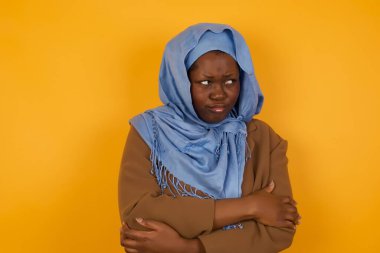 Closeup portrait displeased pissed off angry grumpy pessimistic African American muslim woman with bad attitude, arms crossed looking sideways. Negative human emotion facial expression feelings