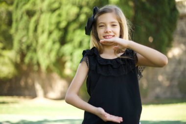 Elleriyle büyük ve büyük bir işaret gösteren genç ve güzel bir kız, ölçü sembolü. Kameraya bakıp gülümsüyor. Ölçüm konsepti.