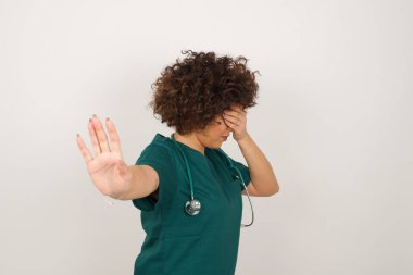 İnsanlar, vücut dili. Tıp üniforması giyen güzel Arap doktor kadın avuçla gözlerini kapatıyor ve herkesten saklanmaya çalışıyor. Bana bakma, görmek istemiyorum, utanıyorum ya da korkuyorum..