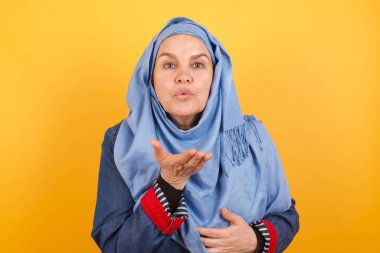 Sevimli, çekici, orta yaşlı, tesettürlü Müslüman kadın kameraya tokat atıyor, sevgisini gösteriyor. 