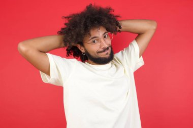 Kızıl duvarın arkasında elleri olan afro saçlı genç adam.   