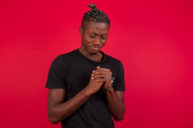 Üzgün, Afro-Amerikan bir adam evde tek başına vakit geçirirken üzgün hissediyor. Yakışıklı, genç, sarışın erkek. Mutsuz ve üzgün bir şekilde kameraya bakıyor. Kapalı alanda duruyor..