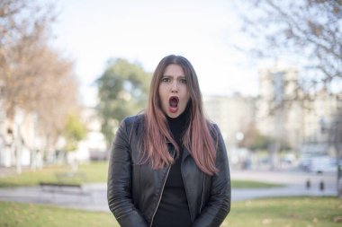 Parkta ağzı açık genç ve güzel bir kadın.