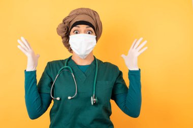 Başarı, başarı konsepti. Neşeli, genç, güzel, Müslüman doktor yeşil üniformalı kadın ellerini kaldırıyor, tıp üniforması giyiyor, mutluluk dolu gözleri büyük başarılarını kutluyor..