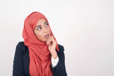 Yüz ifadeleri ve duygular. Düşünceli Müslüman kadın siyah ceket giyiyor ve kafasının altına tesettür takıyor. Arkadaşının doğum günü partisinde ne giyeceğine karar veremezken şüpheli bakışlar atıyor. 
