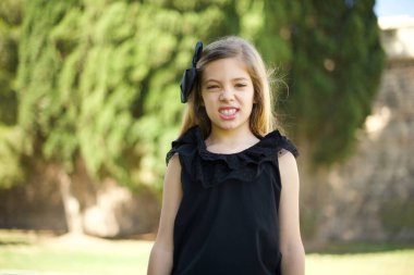 Siyah elbiseli çılgın tatlı kız dişlerini öfkeyle sıkar, gürültüden rahatsız olur, şık kıyafetler giyer., 