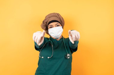 Yüz maskeli, şaşırmış bir kadının yakın plan portresi kamerayı işaret ederek, 