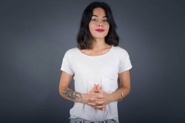  Gri arka planda yalnız bırakılmış kendine güvenen yüzüyle el ele tutuşan kadın.