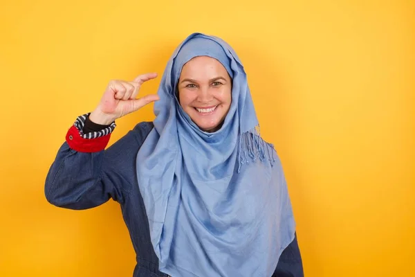 中年のイスラム教徒の女性は 小さなサイズ 測定シンボルを示す手で 孤立した背景のジェスチャーの上に カメラを見ている笑顔 測定コンセプト — ストック写真