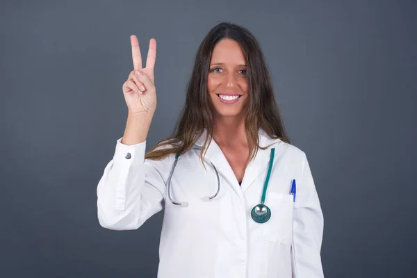 Jonge Dokter Vrouw Medisch Uniform Staande Tegen Grijze Muur Tonen — Stockfoto