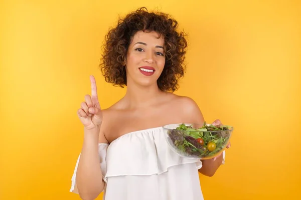 Mujer Árabe Joven Con Ensalada Pie Contra Pared Mostrando Apuntando —  Fotos de Stock