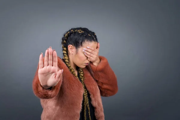 People, body language. Young European blue eyed woman covers eyes with palm and doing stop gesture, tries to hide from everybody. Don't look at me, I don't want to see, feels ashamed or scared.