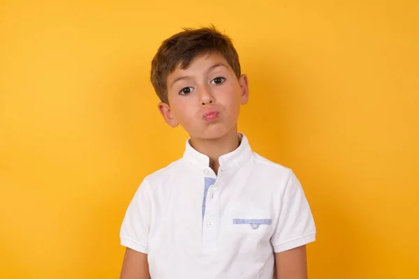 Χαριτωμένο Αγόρι Φυσάει Χείλη Ενάντια Στον Κίτρινο Τοίχο — Φωτογραφία Αρχείου