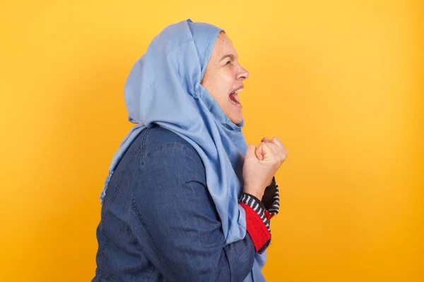 ヒジャーブの中年のイスラム教徒の女性は興奮し 勝利を達成するために喜び クレンチ拳 閉じた目で興奮の叫び 大学ですべての試験に合格するために幸せ 成功した人 — ストック写真