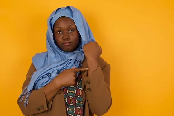 Beautiful young African American muslim woman over isolated background In hurry pointing to watch time, impatience, upset and angry for deadline delay