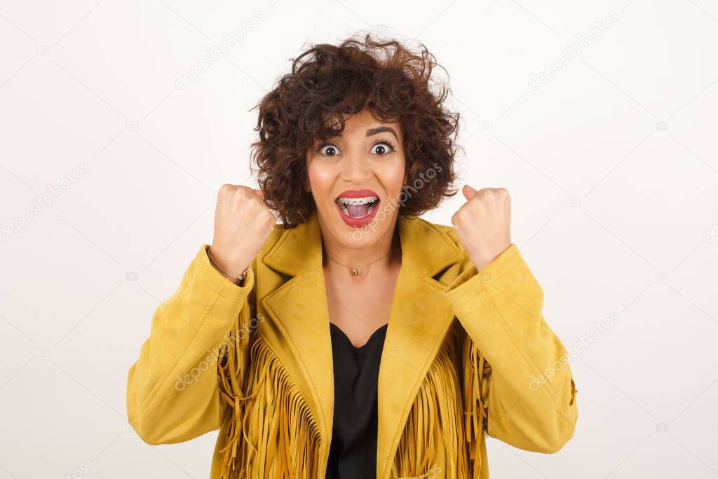  young woman rejoicing her success and victory clenching her fists with joy.Lucky woman with hat being happy to achieve her aim and goals.Positive emotions, feelings.