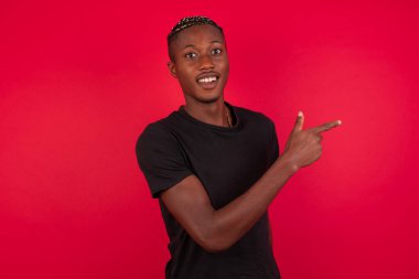 Şuraya bakın! Kırmızı arka planda siyah tişört giyen yakışıklı Afro-Amerikan bir adam.