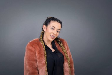 Utangaç kız kameraya bakarak gülümsüyor. Beyaz tenli çekici kız gri stüdyo geçmişine karşı zımparalıyor. Utangaç..