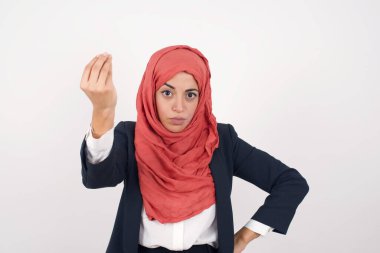 What the hell are you talking about. Shot of frustrated Beautiful muslim woman  wears black blazer and hijab gesturing with raised hand doing Italian gesture, frowning, being displeased and confused with dumb question.