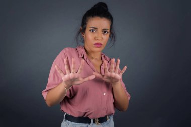 Güzel esmer kız, izole edilmiş arka planda korku ve korku dolu ve tiksindirici bir ifadeyle iki elinle hareket etmeyi kes.