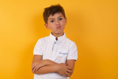 Sarı duvara yaslanmış, kolları bağlı sevimli bir çocuk.   