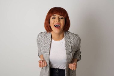 Şık, modern bir bayanın yakın portresi dalgalı saç stili yumruklarını kaldıran parlak gri arka planda büyük gözler ve geniş bir ağız..