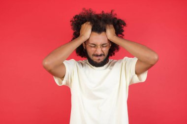 Kızıl duvarda başı ağrıyan afro saçlı genç adam.   