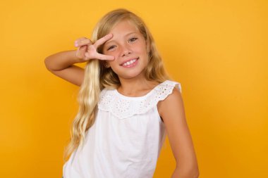 Sarı arka planda el kol hareketi yapan tatlı kız. 