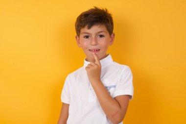 Sarı duvara gülümseyen sevimli çocuk.  